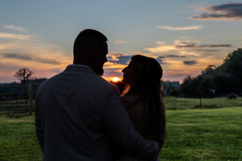 Silhouetted wedding couple in front of a pasture and sunset
