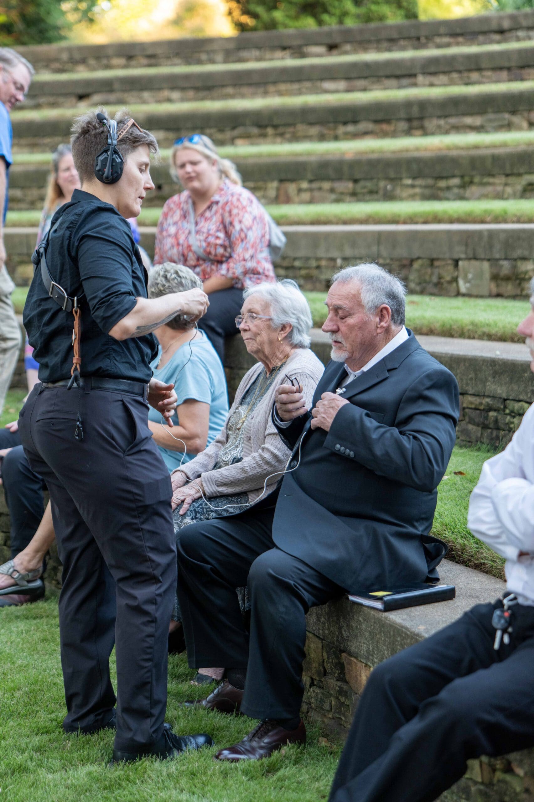 videographer putting a lavalier microphone on the officiant before a wedding ceremony